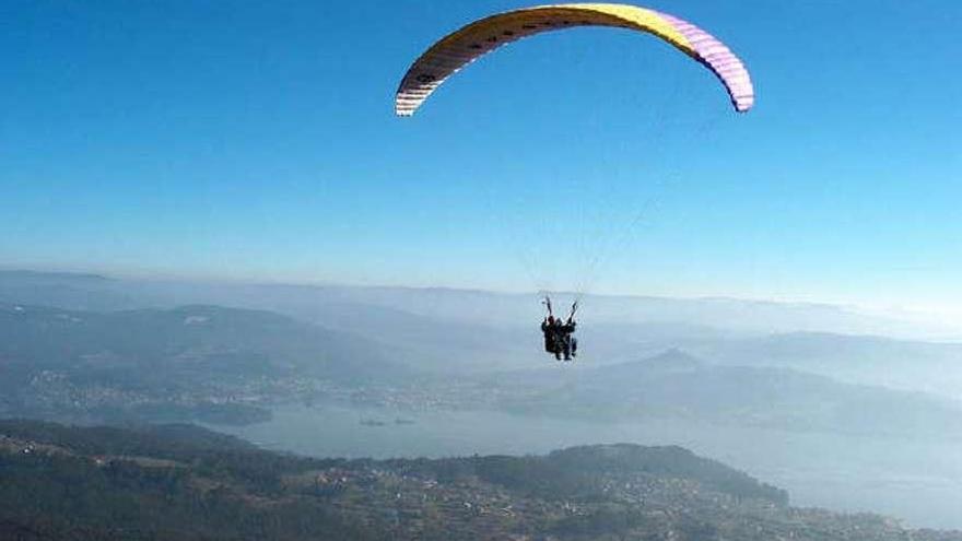 Un parapente biplaza sobrevuela Domaio tras despegar en el Monte Xaxán. // G.N.