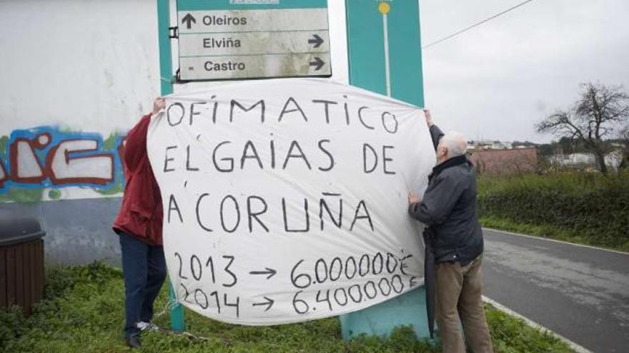 Dos vecinos del ofimático cuelgan una pancarta durante una protesta en Alfonso Molina. / 13fotos