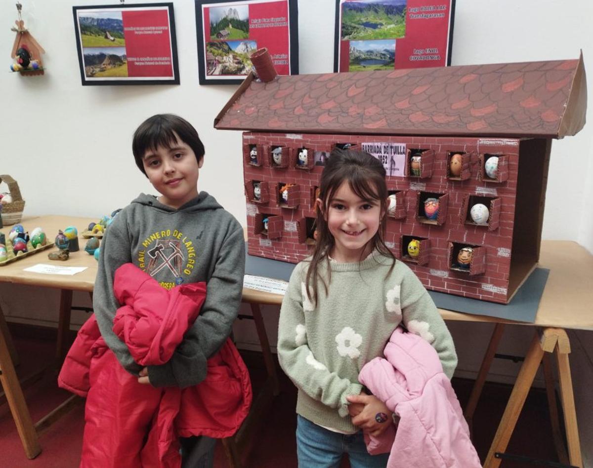 Nel Menéndez y Clara Pueyo, ante el trabajo dedicado a una barriada de Tuilla en la exposición de Huevos Pintos.