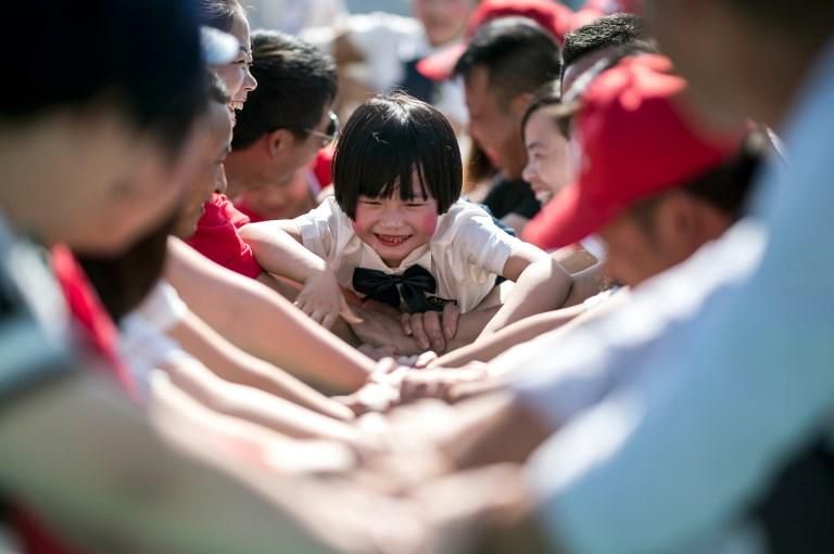 Padres jugando con sus hijos en Shanghai/ AFP PHOTO / Johannes EISELE