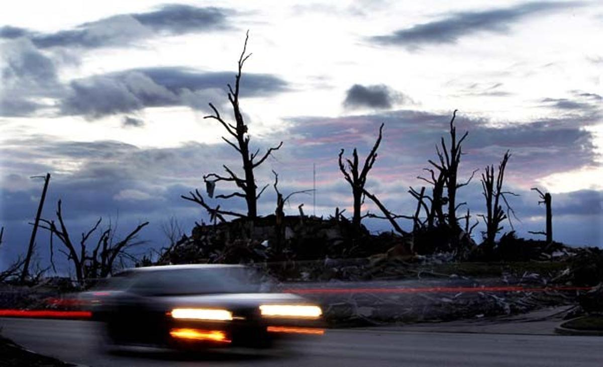 Un automòbil passa davant les restes d’una casa a Joplin, localitat de l’estat de Missouri (EUA) que diumenge passat va quedar arrasada per un tornado que fins al moment ha causat 123 morts.