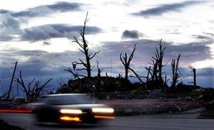 Un automòbil passa davant les restes d’una casa a Joplin, localitat de l’estat de Missouri (EUA) que diumenge passat va quedar arrasada per un tornado que fins al moment ha causat 123 morts.