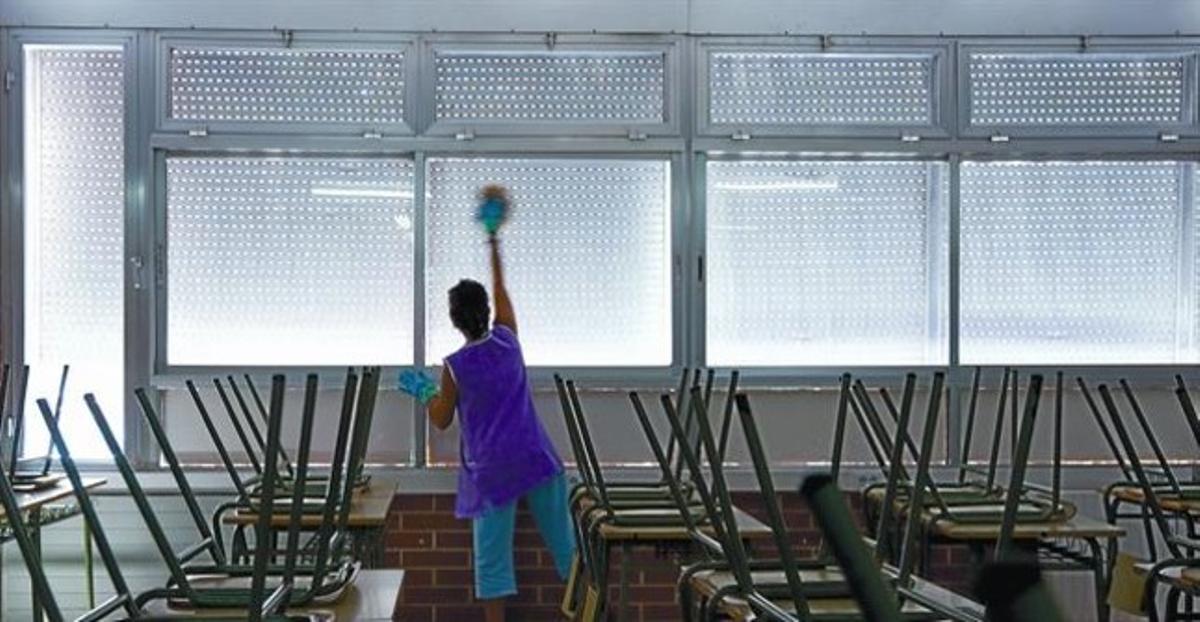 Una trabajadora limpia un aula del colegio Joan Coromines, de Barcelona, ayer.