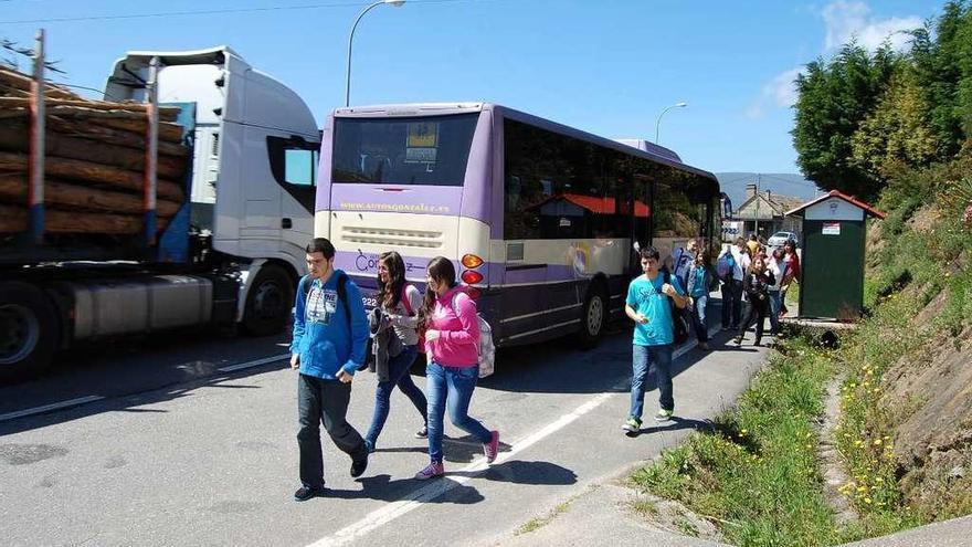 Unos jóvenes bajan del autobús en la parada de la carretera N-550 junto al colegio de Cesantes. // FdV