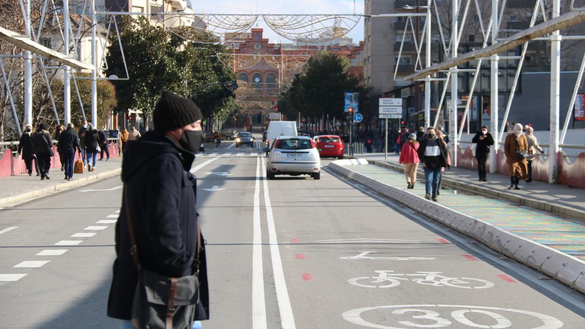 Un viandante cruza una calle de Terrassa en la que se ha pintado la limitación de 30 km/h junto a las siluetas de bicicleta y patinete