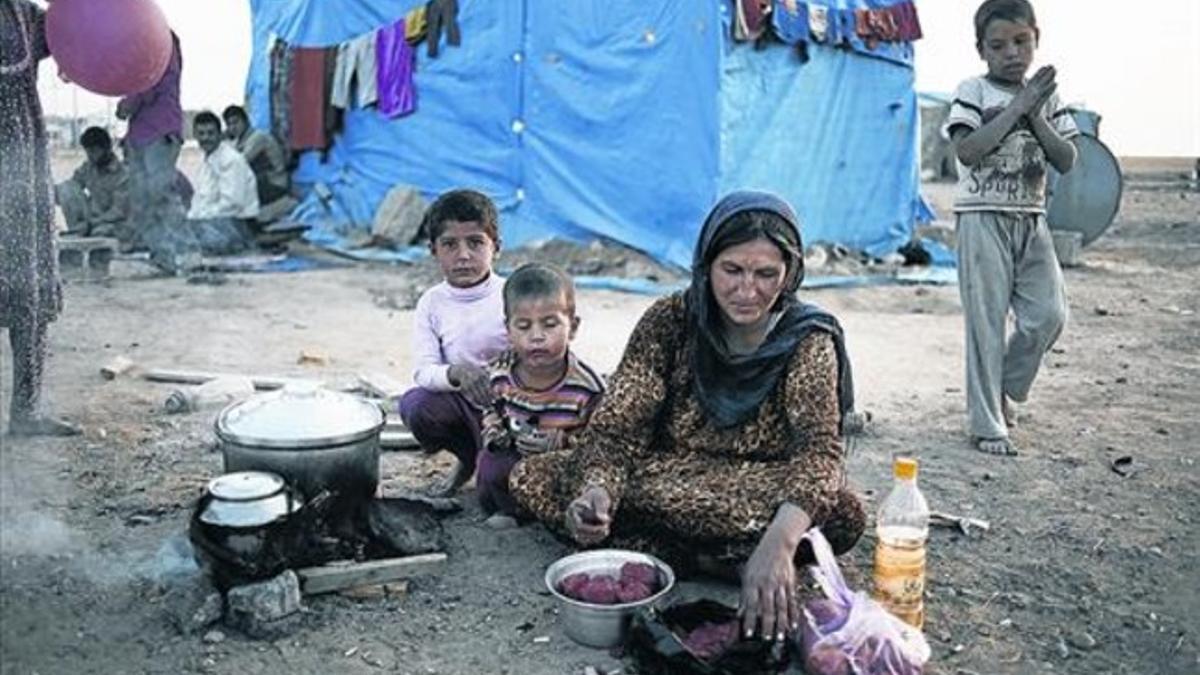 Una mujer prepara la comida para ella y sus tres hijos en un campo de refugiados sirios.