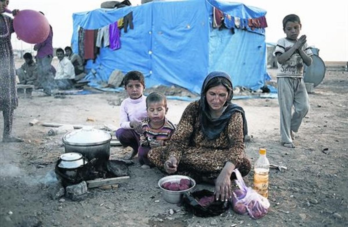 Una dona prepara el menjar per a ella i els seus tres fills en un camp de refugiats sirians.