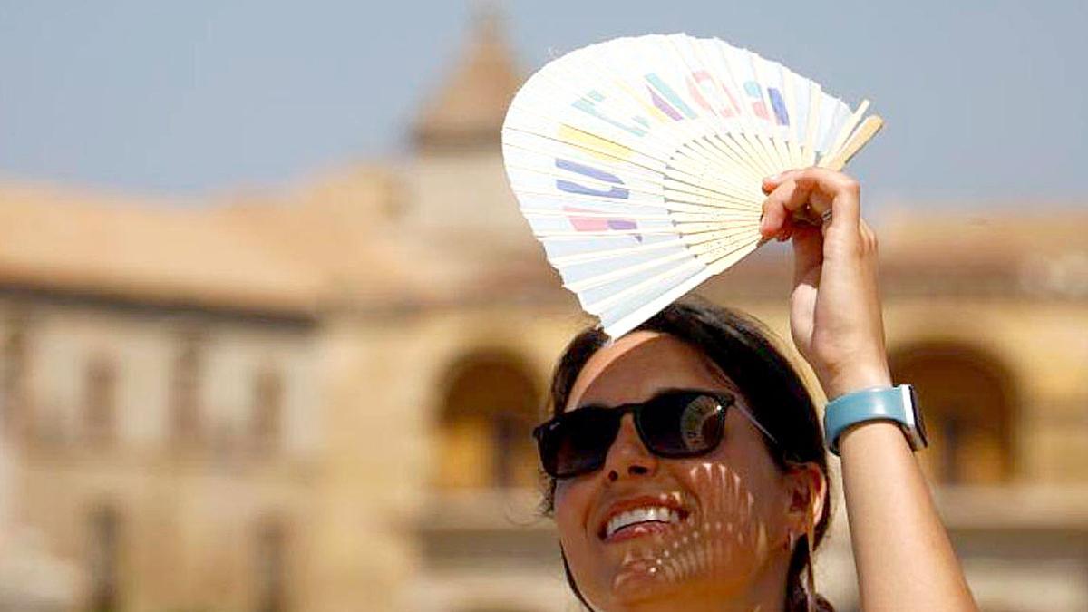 Una mujer se protege del sol con un abanico.
