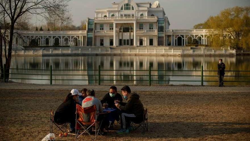 Un grupo de personas juega a las cartas, ayer, en un parque de Pekín. // Reuters