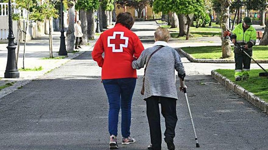 Una voluntaria de la Cruz Roja acompaña a una persona mayor.