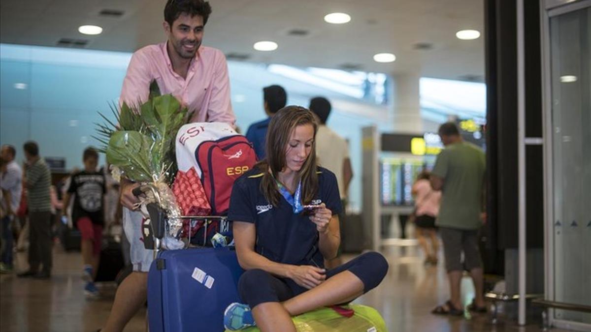 Vall observa la medalla mientras es llevada por su marido, Alberto, en el aeropuerto de Barcelona.