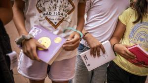 Tres estudiantes con libros de lectura en la mano.