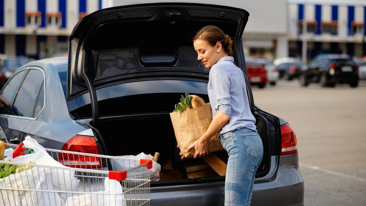 Una mujer introduce sus compras en el maletero del coche