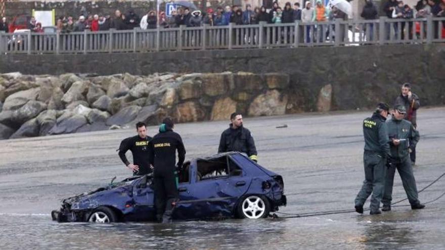 El coche llega a tierra tras media hora de arrastre desde donde estaba hundido en el puerto de A Guarda. / r. g.