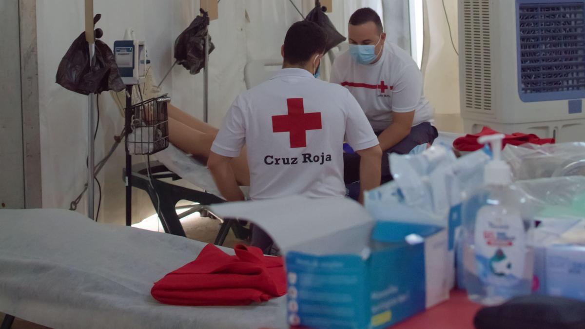Voluntarios de Cruz Roja atienden a una persona en el puesto que la institución tiene en el recinto ferial.