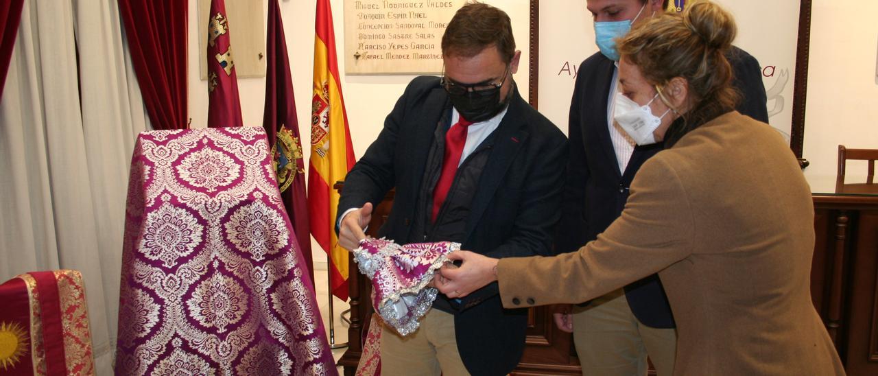 Diego José Mateos, Ignacio Arcas y Nines Mazuecos contemplan el vestido del Niño de la Patrona.