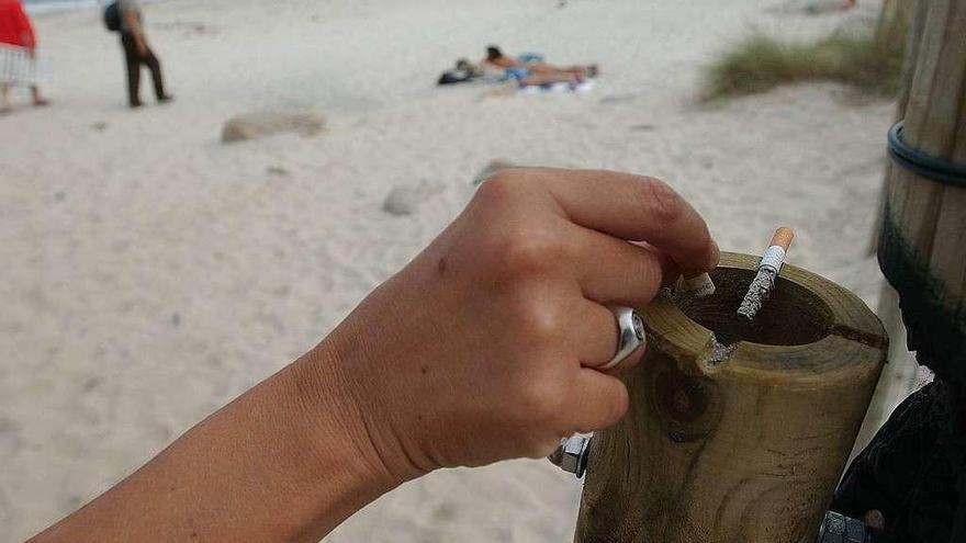 Una mujer deposita una colilla en un cenicero antes de bajar a la playa.