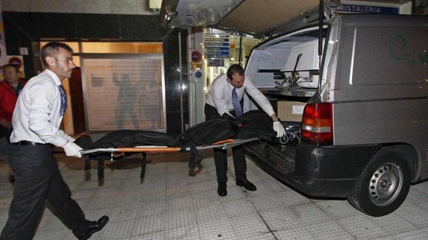 Los empleados de la funeraria trasladan el cadáver a un furgón, ayer por la noche en Ponteareas. jorge santomé