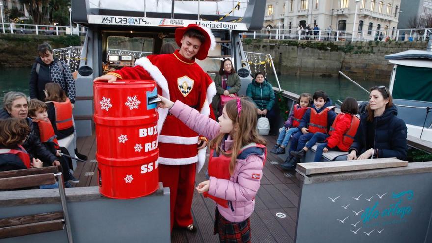 Una niña deposita su carta en el buzón en presencia del paje real, ayer, en el Barco de la Navidad. | Ángel González