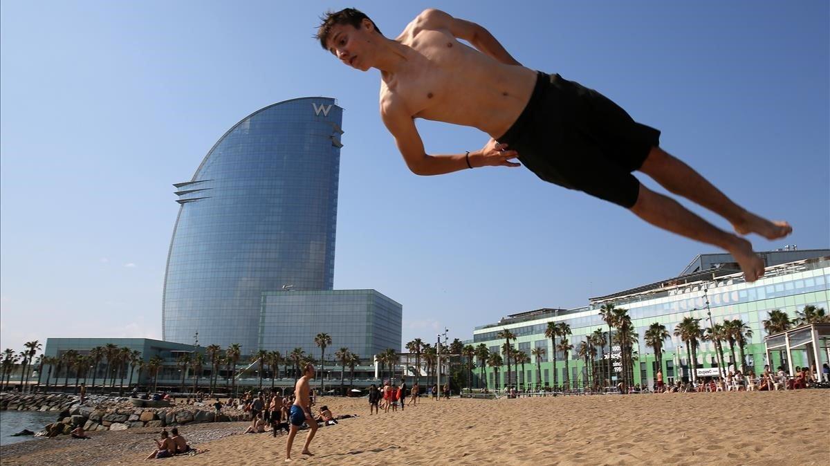 En los primeros dias de baño en la Barceloneta, el pasado 30 de mayo, unos jovenes saltan en trampolín, parece por la postura y la mirada que están por encima de todo, hasta del covid-19.