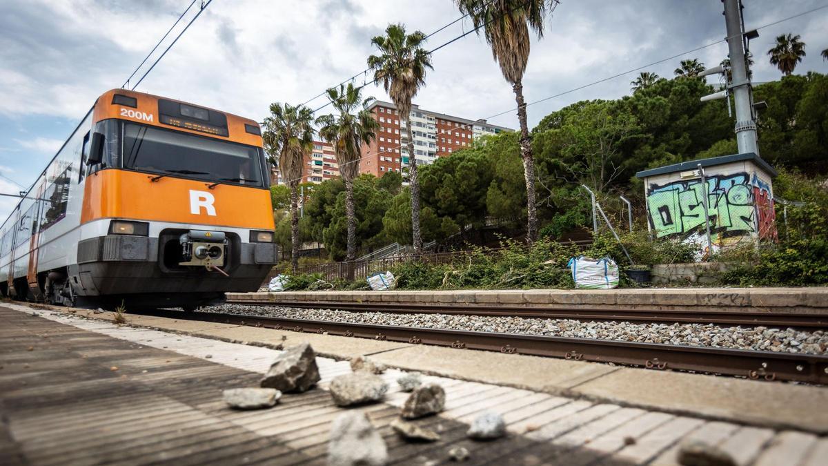 Unas piedras, junto a las vías, al paso de un tren de Rodalies.
