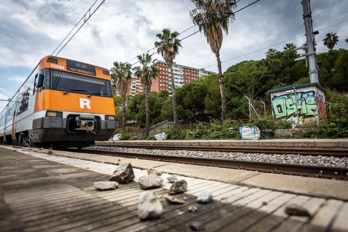 Unas piedras, junto a las vías, al paso de un tren de Rodalies.