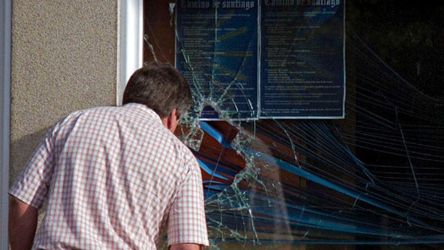 Un vecino de la zona observa, a través de la ventana rota, el estado interior del local.