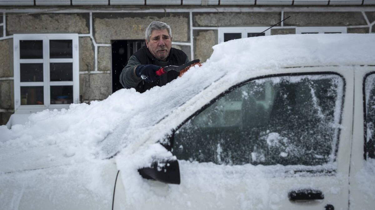 Un hombre limpia la nieve de su coche durante la borrasca Ingrid en Ourense