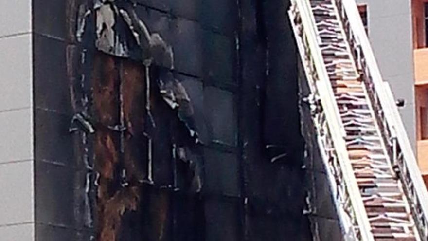 Los bomberos retiran los paneles afectados por las llamas de la fachada del hospital.