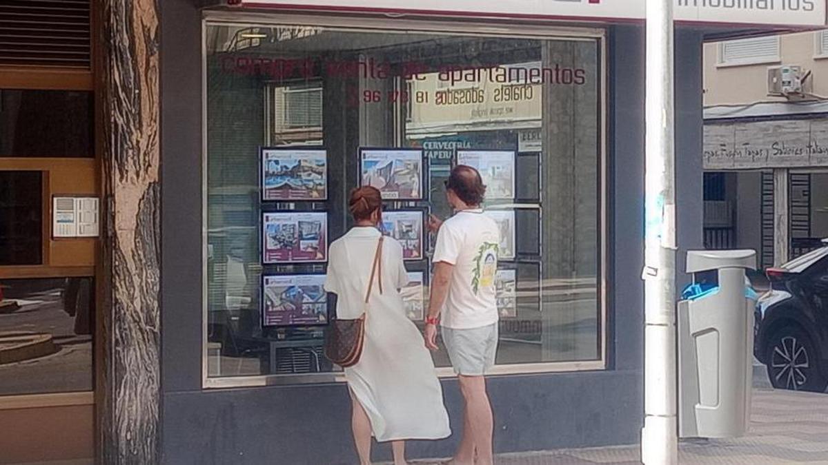 Un pareja observa el escaparate de una inmobiliaria de Cullera en una imagen de archivo.