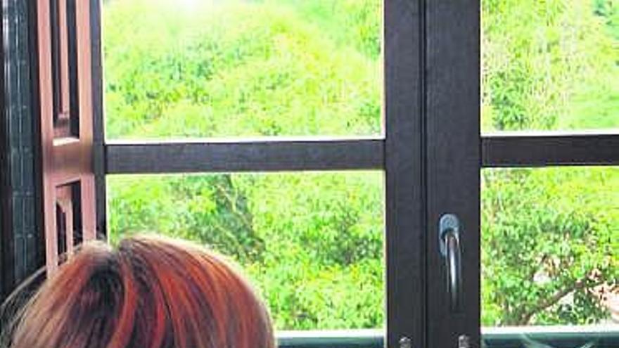 Elisa, de espalda, ante una ventana de su casa.