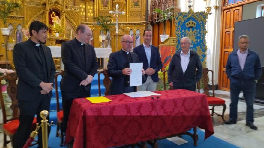 El párroco muestra el título de basílica menor flanqueado por el representante del arzobispado y el alcalde