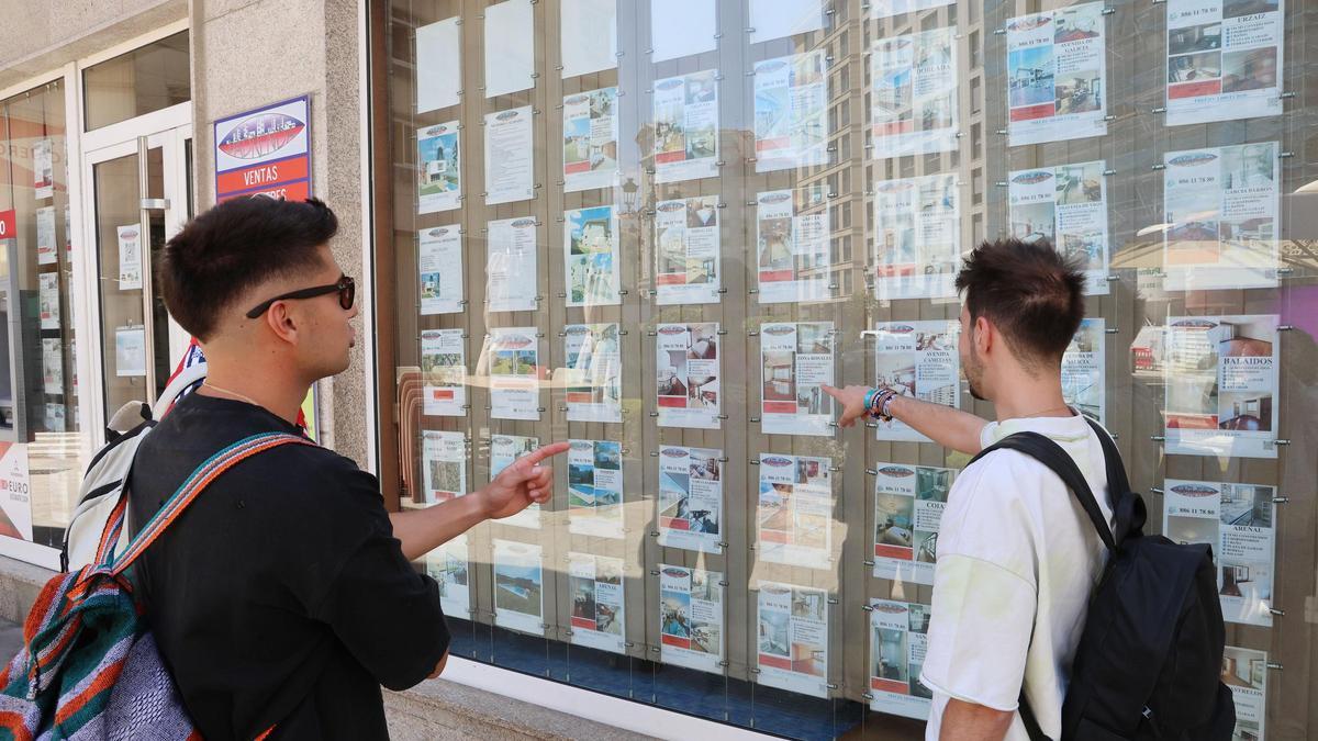 Jóvenes viendo anuncios de pisos en una inmobiliaria del centro de Vigo.