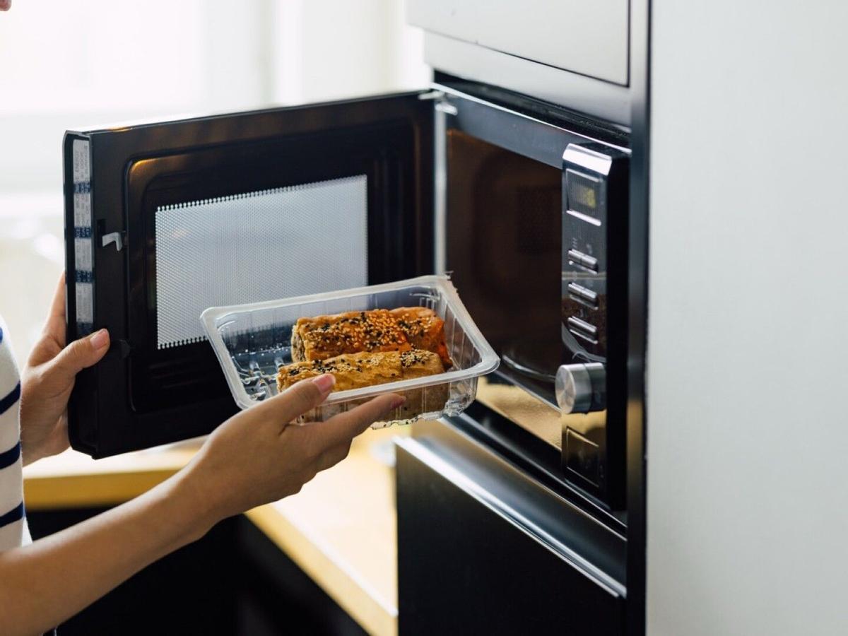 Envase de plástico con comida a punto de ser introducido en el microondas