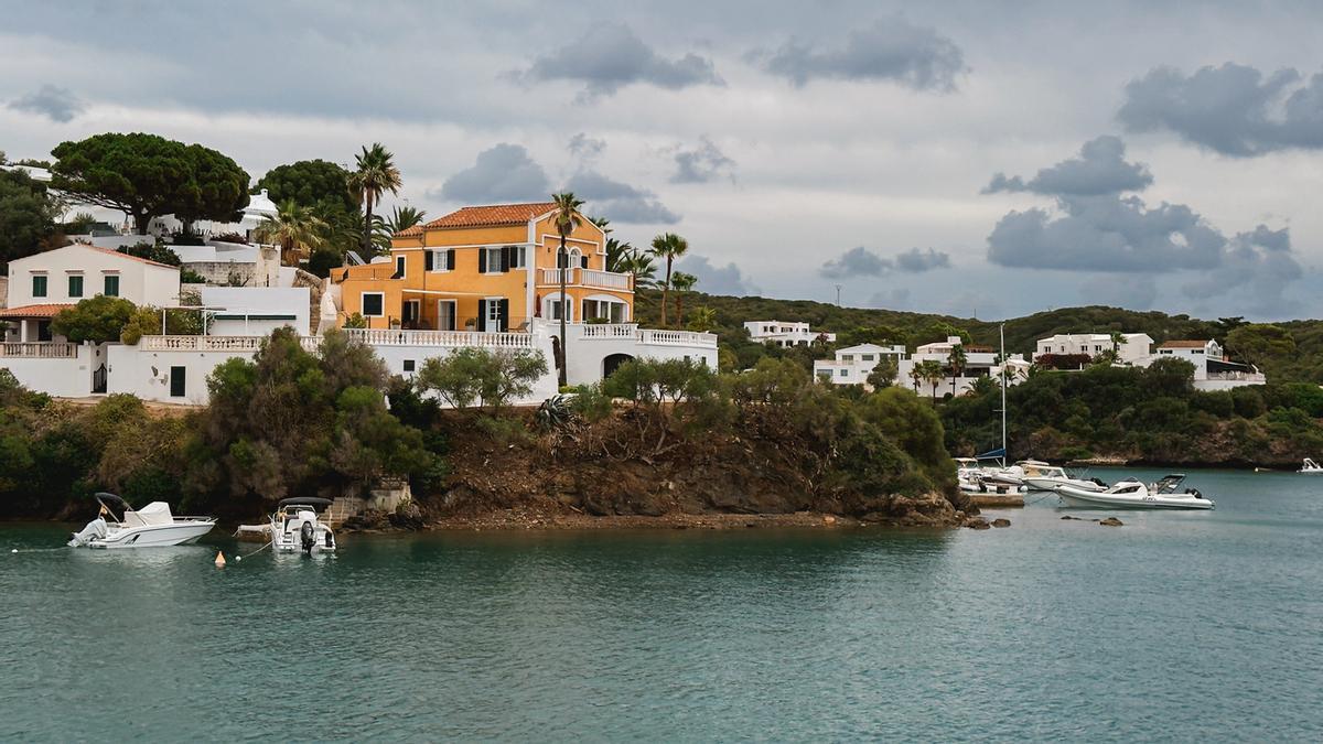 Villa costera con paredes naranjas y detalles blancos con vistas a una bahía tranquila