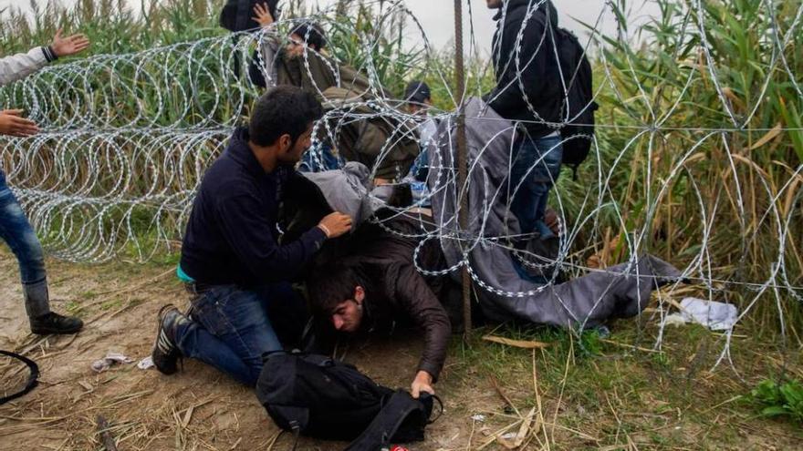 Refugiados sirios cruzan la alambrada en la frontera entre Hungría y Serbia.