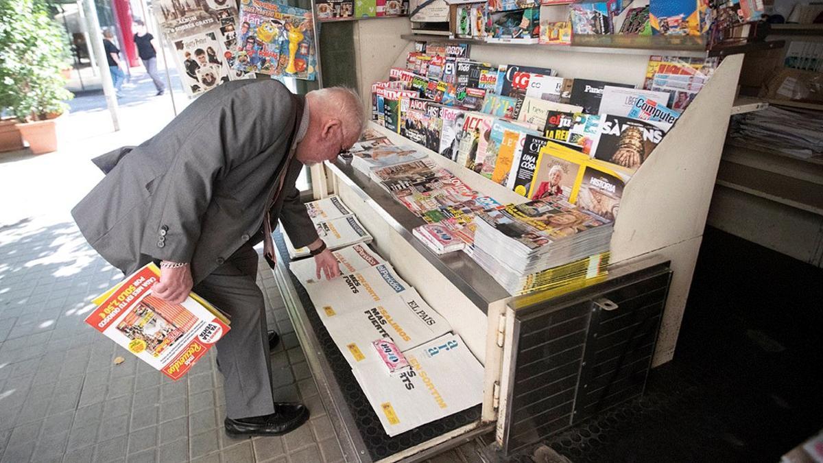 Un hombre compra el diario en un quiosco de Barcelona, el 25 de mayo