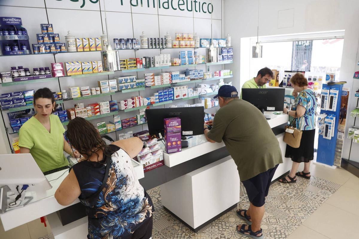 Varias personas son atendidas en una farmacia de Alfafar.