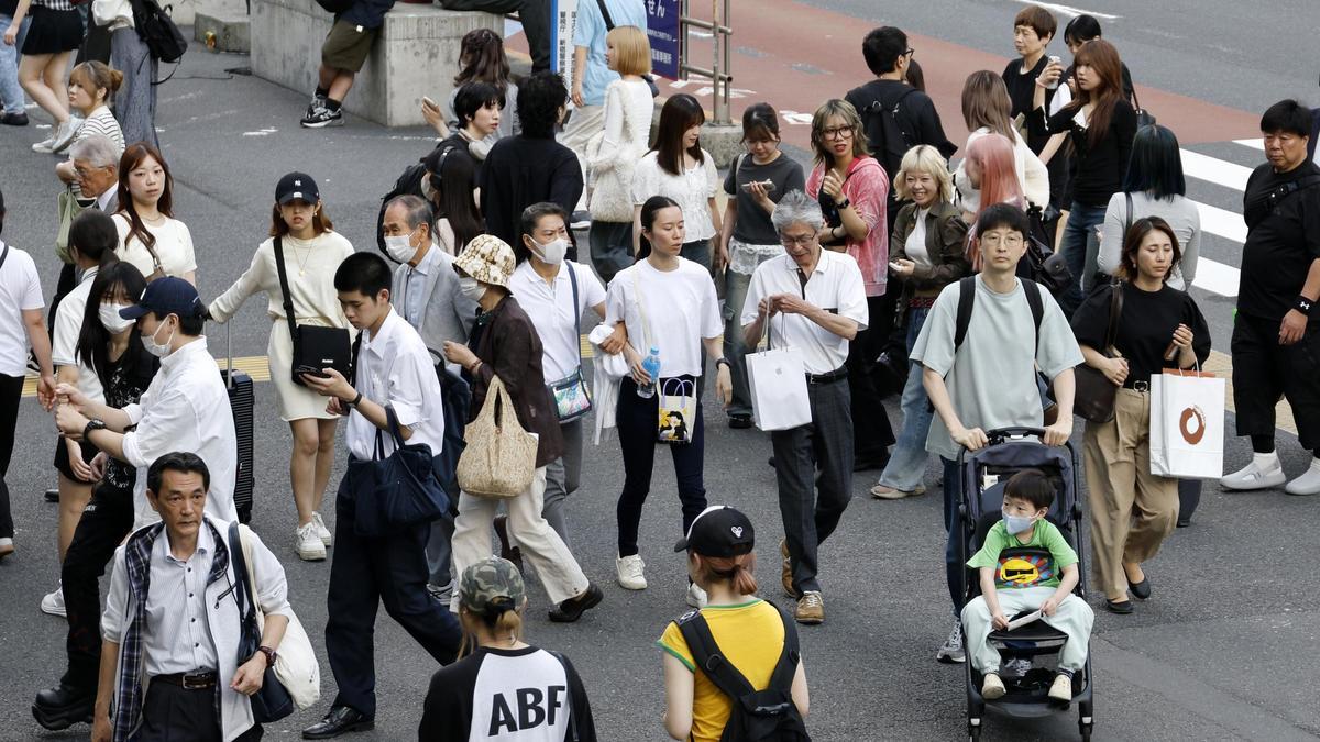 Un padre pasea a su hijo en carro en el distrito comercial de Shinjuku, en Tokio.