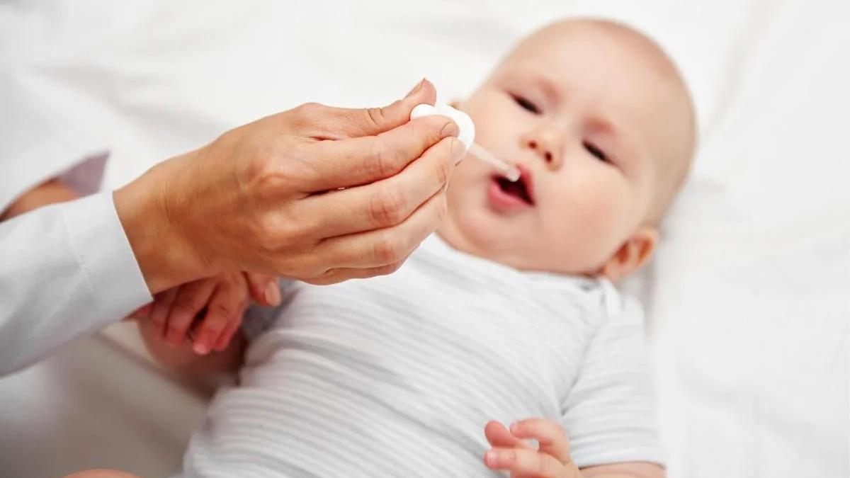 Un sanitario administra una vacuna oral a un bebé.