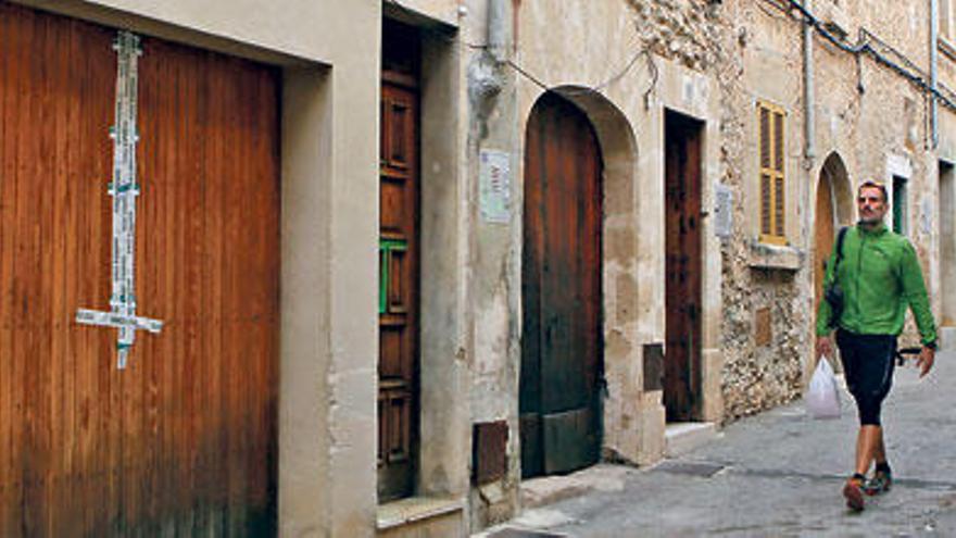 La puerta precintada del domicilio de Llorenç Colom, en el número 18 de la calle Gonzalo Ferragut de Pollença. En la imagen pequeña, Llorenç Colom en una foto antigua.