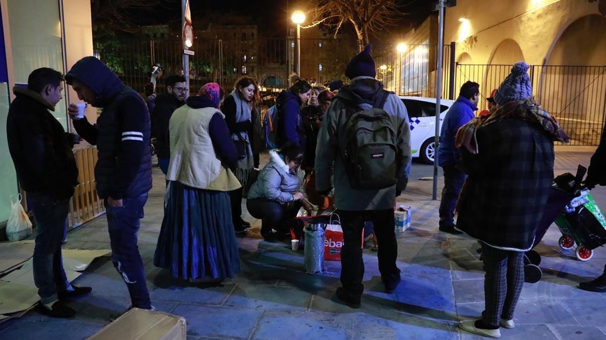 Voluntarios de una iglesia evangélica reparten cena a los sintecho de la plaza de Sant Pau.