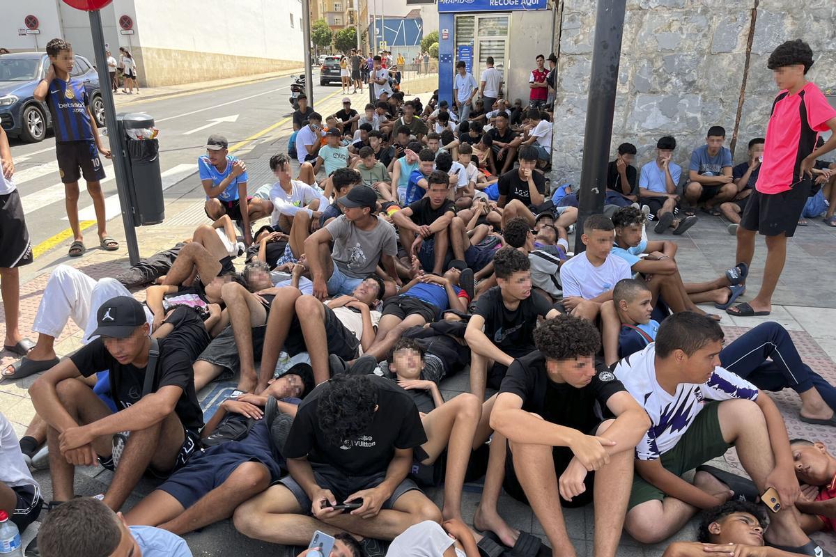 FOTODELDIA CEUTA, 10/08/2026.-Multitud de menores migrantes esperan para su filiación frente a la Jefatura Superior de la Policía Nacional en Ceuta este lunes. La situación en Ceuta sigue lejos de normalizarse, con campamentos provisionales para muchos migrantes y miles de menores a la espera de una solución, y continúa marcando la disputa entre el Gobierno y el PP, que mantiene el pulso para que tres ministros comparezcan en el Senado aunque desde el Ejecutivo solo piensen hacerlo en el Congreso. -EFE/ Reduan