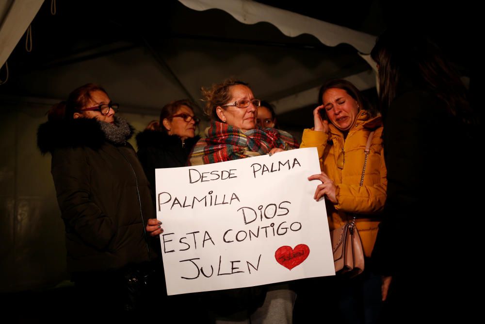 Women cry as they hold a banner that reads, ...