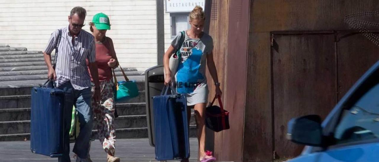 Unos turistas caminan con maletas por las calles de Oviedo.