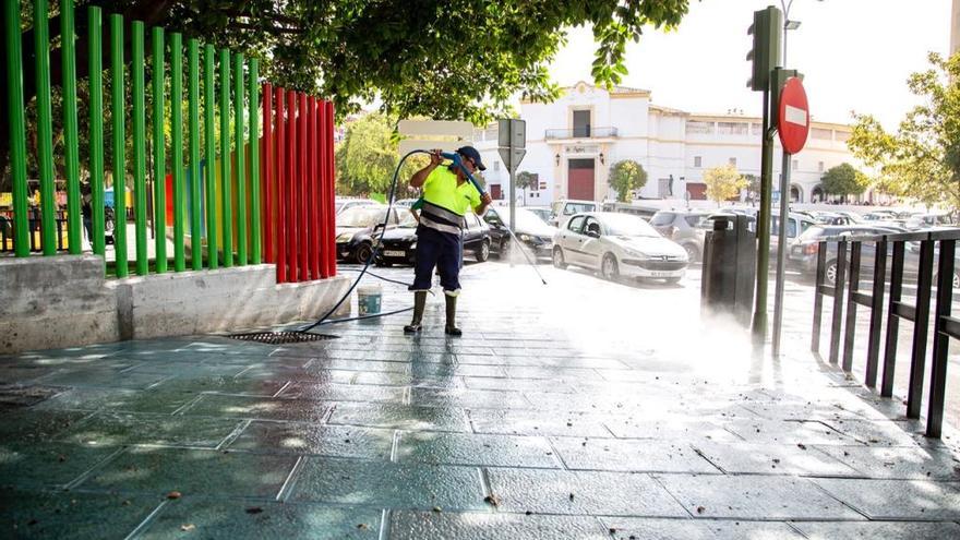 Un operario baldea una acera en la barriada de Plaza de Toros.