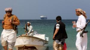 Hombres armados en la costa de Yemen, con el carguero Galaxy Leader al fondo.