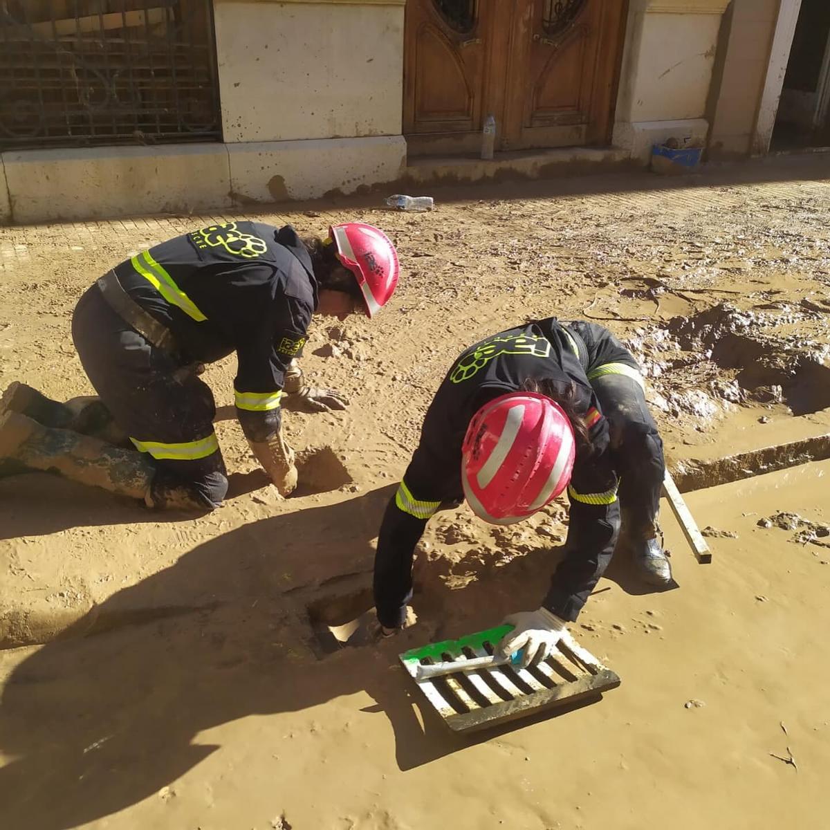 Dos voluntarios retiran barro de una alcantarilla dañada en Algemesí, en una imagen tras la dana.