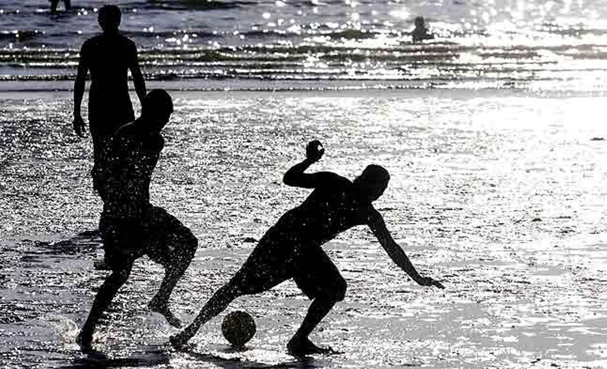 Els veïns de Montevideo (Uruguai) juguen a futbol a la platja de la ciutat de Ramírez durant el primer dia d’estiu.