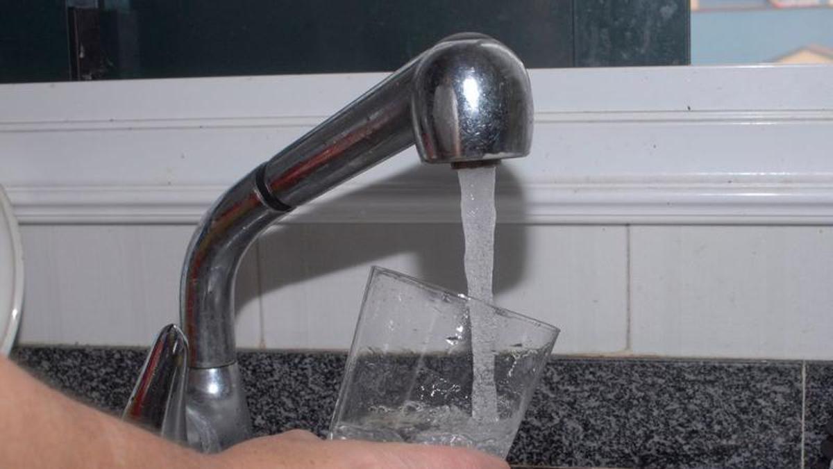 Una vecina llena un vaso con agua del grifo.